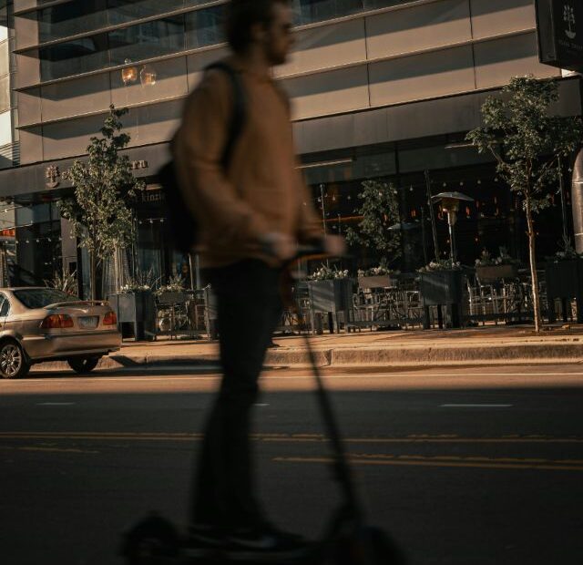 Persona usando patinete eléctrico en la ciudad al atardecer