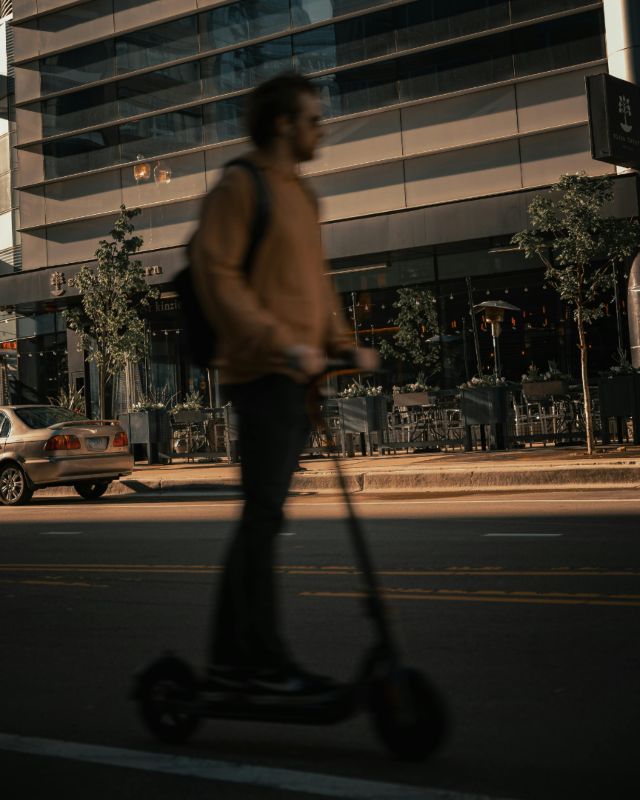 Persona usando patinete eléctrico en la ciudad al atardecer