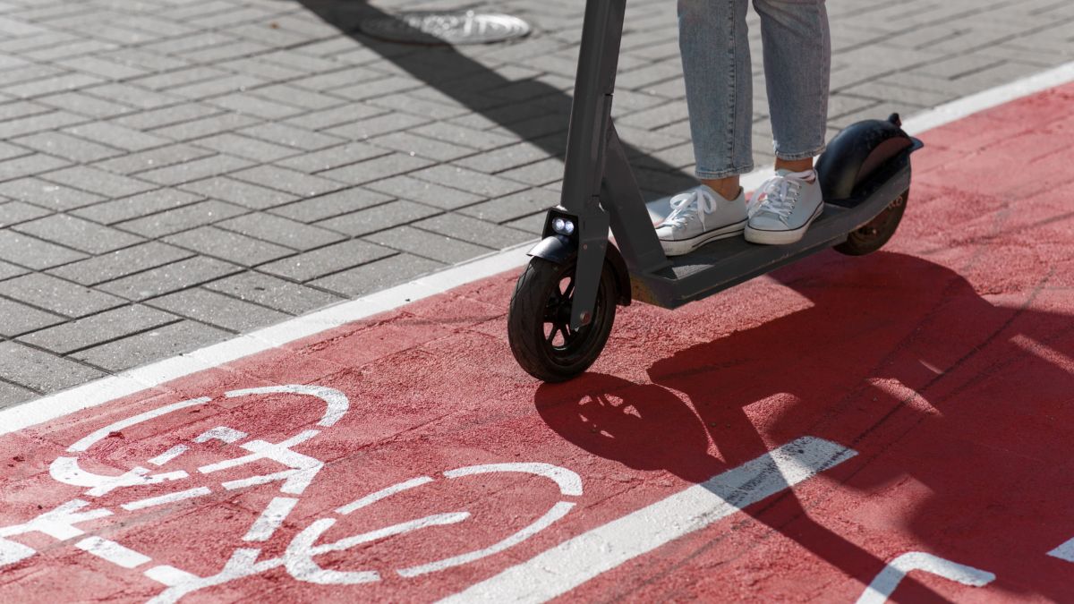 Persona en patinete eléctrico en avenida amplia