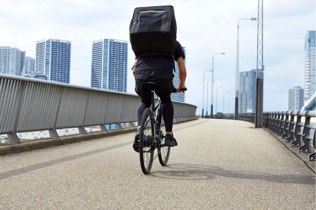 Ciclista urbano con mochila en bicicleta eléctrica